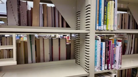 Library shelves showing gaps, symbolizing funding cuts and missing resources Stock Footage 334647199