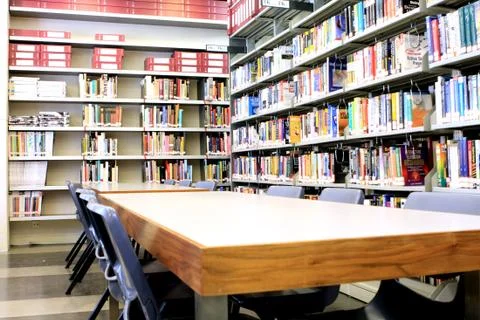 Library stacks of books with table Stock Photos