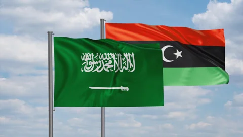 Libya and Saudi Arabia flag waving together in the wind on blue sky, cycle Stock Footage 244064450