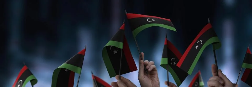 Libya flags in their hands on a blurred urban background Stock Illustration