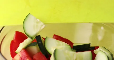 Liced cucumber is poured into a bowl with Red Tomato. Close-up. Stock Footage 250176997