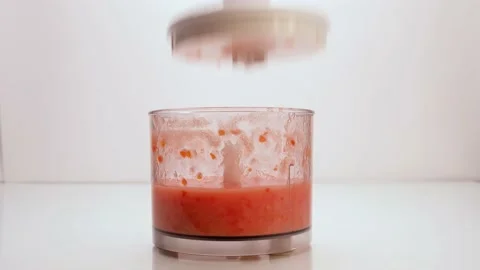 The lid of the blender with ground tomatoes opens. Women's hands take the cup Stock Footage 154708801