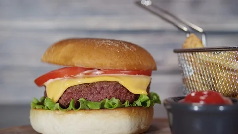 Lid dropping on vegan plant based burger with fries on rustic cutting board Stock Footage 114121882
