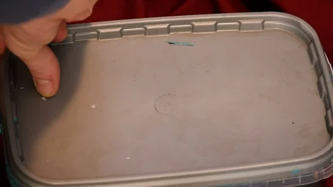 Lid is removed &amp; blue paint is mixed using a paint brush Stock Footage 100975378