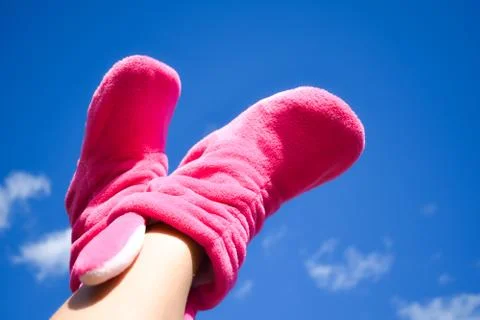 Lie down to the top. Clear blue sky and female legs in socks. Stock Photos