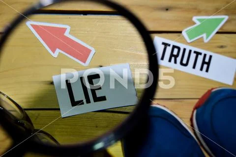 Lie or Truth opposite direction signs in magnifying with sneakers Stock Photos