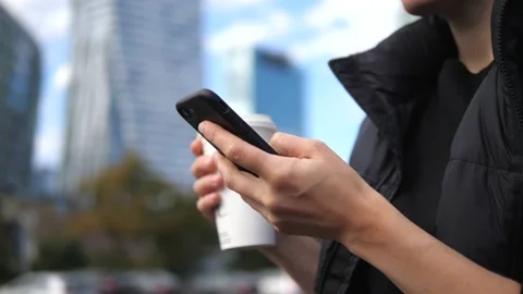 Life on the go. Close up of hand using smartphone and another holding takeaway Stock Footage 150567880