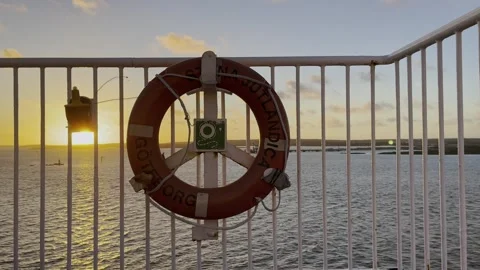 Life ring on a white railing of a ship in the wind with sunset and sea on Stock Footage 256622904