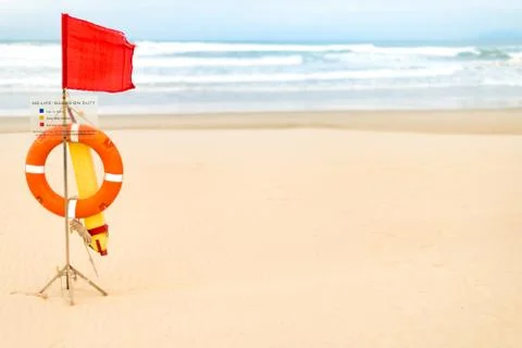 Life saving objects with red flag on beach. Stock Photos