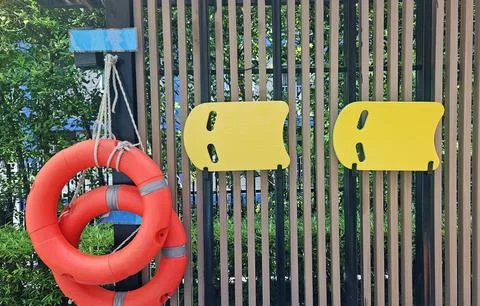 Life saving rubber ring, Yellow and Blue Swimming form hanging on wooden wall 스톡 사진