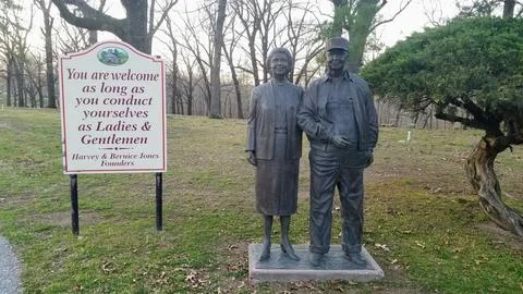 Life-Sized Bronze Statue of Two Figures and Informative Signage in Outdoor Park Stock Photos