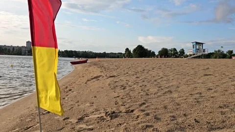 Lifeguard flag on empty sandy city beach with rescue tower horizontal view Stock Footage 336189637