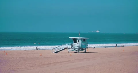Lifeguard tower on beach with ocean waves and people relaxing 스톡 동영상 339519726