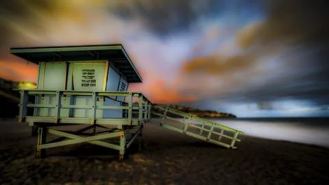 Lifeguard tower on beach at sunset with dramatic clouds and ocean view 写真素材