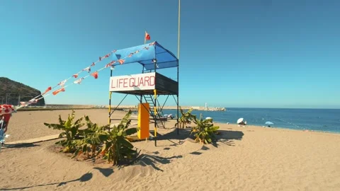Lifeguard Tower with Flags Waving on a Sunny Day at Selinus Beach, Gazipasa Stock Footage 294744727