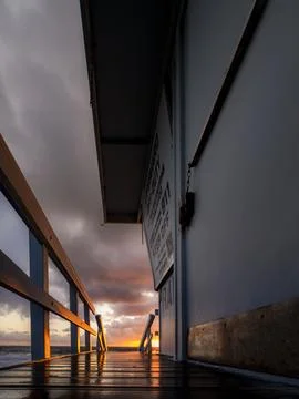 Lifeguard tower walkway at sunset with dramatic clouds and wet wooden planks Foto stock