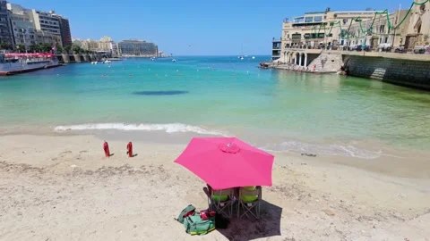 Lifeguards under parasol keep the closed Balluta Bay beach empty due to Stock Footage 297839210