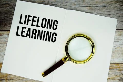 Lifelong Learning text message written on paper note with magnifying glass .. Stock Photos