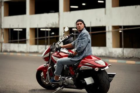 Lifestyle of a motorcyclist, a handsome biker with long hair on a red classic Stock Photos
