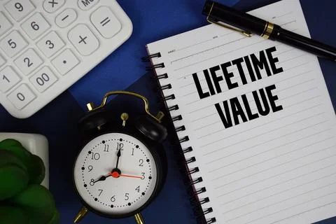Lifetime Value text written on notepad with calculator and alarm clock on n.. Stock Photos