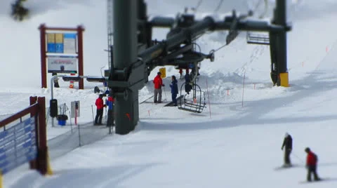 Lift operator loading skiers and snowboarders onto chairlift Stock Footage 24759596