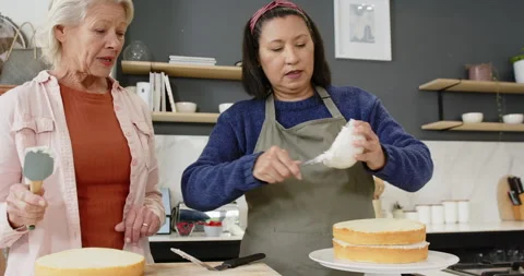 Lifting 2nd layer, Diverse senior friends are stacking, frosting cake on stand Stock Footage 314028740