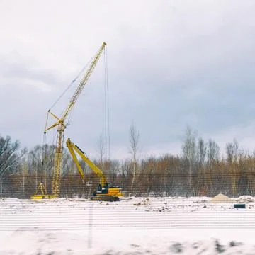 Lifting construction crane on a Construction site in a field near a forest in Stock-Fotos