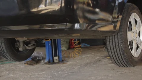 Lifting equipment lowering a car in a workshop Stock Footage 87794937