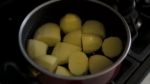Lifting glass lid from pot with boiling peeled potatoes on stove close up. Vidéo 340036105