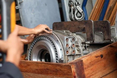 Lifting heavy mechanical transmission component with a crane. Photos