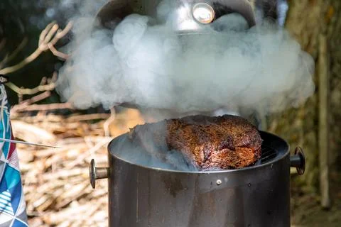 Lifting the lid to check on a large beef brisket on a smoker Stock Photos