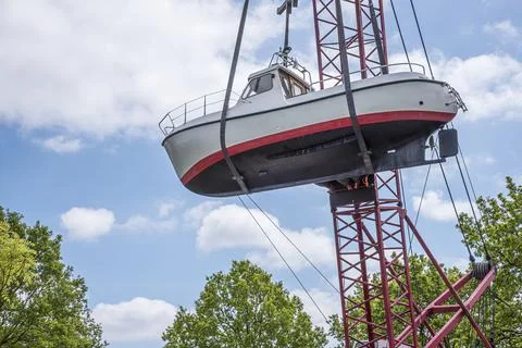 Lifting a motorboat over the treetops with a crane Stock Photos