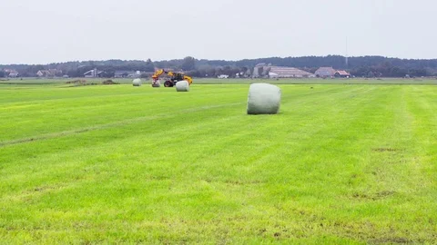 Lifting a plastic wrapped hay bale Stock Footage