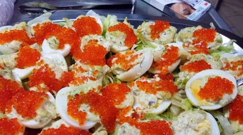 Lifting up a roe topped chicken egg, infront of more eggs, on a metal plate Stock Footage 63055352