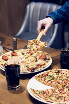 The lifting slice of hot pizza in cafe Stock Photos