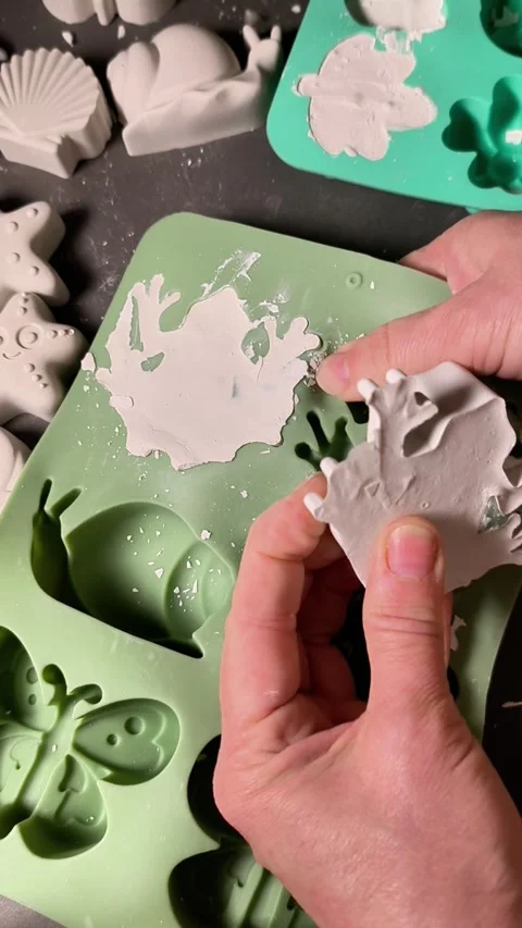 Lifting solidified plaster figure from mold, hands removing crafted shape, Stock Footage 342263640