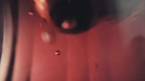 Lifting tea infuser out of red liquid creating tiny bubbles inside the Stock Footage 131714370