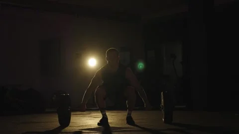 Lifting weights in a dim gym with focused strength training exercises at night Stock Footage 331019542