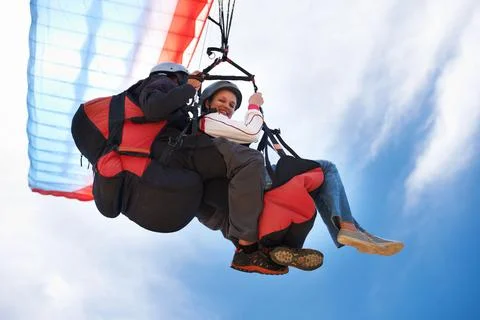 Light as air. Low angle view of two people doing tandem paragliding l. Stock Photos