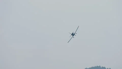 Light aircraft in steep banking turn against grey sky at Gijon festival 動画素材 336260888