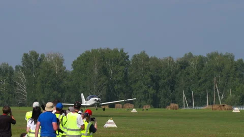 Light airplane taking off past planespotters at Mochishche Airfield Stock-Footage 341696523