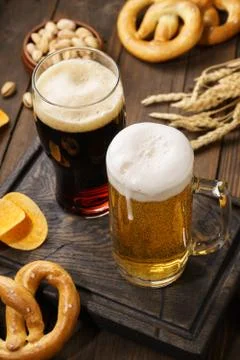 Light and dark beer with various snacks on a wooden background. Stock Photos