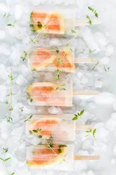 Light and refreshing grapefruit and thyme popsicles on a bed of ice. Stock Photos