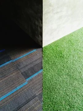 Light and shadow on the corner concrete wall with grass and gray carpet. Stock Photos