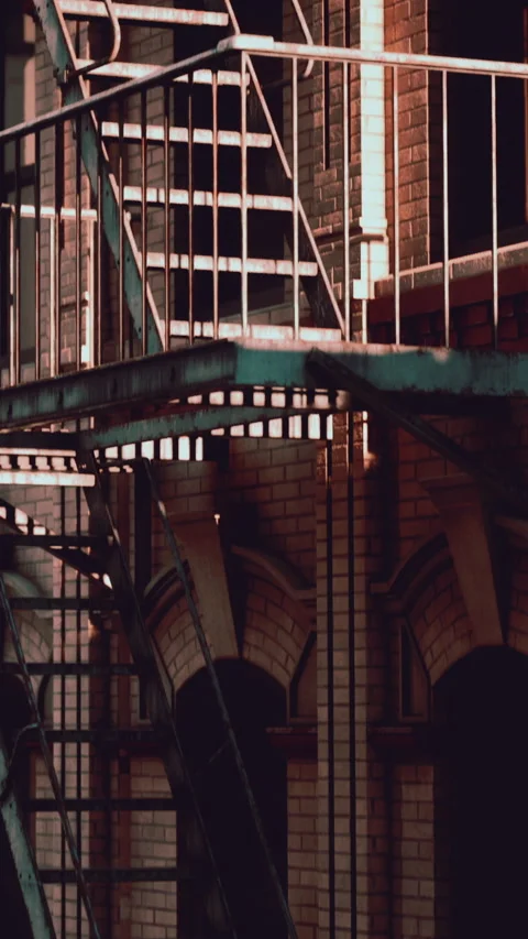 Light and shadow on a fire escape next to a brick building during evening Stock Footage 339099352