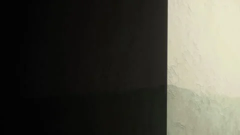 Light and shadow play on the wall in a simple indoor room during the day Stock Footage 348779696