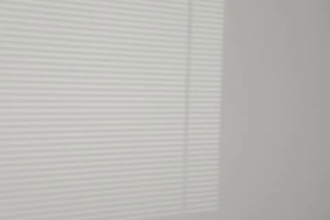 Light and shadow from window shutters on white wall, space for text Stock Photos