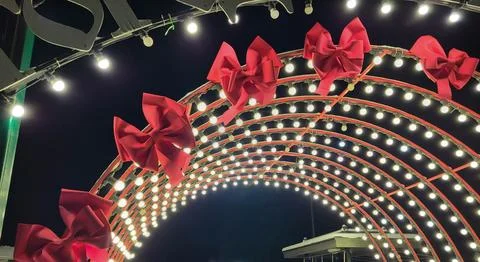 A light arch with red bows in the park on New Year's Eve. Stock Photos