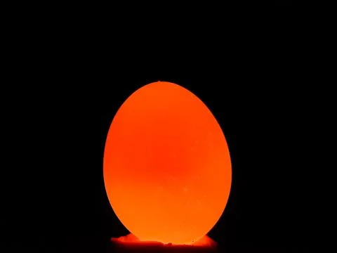 The light is on the back of the egg and the egg is bright yellow. Stock Photos