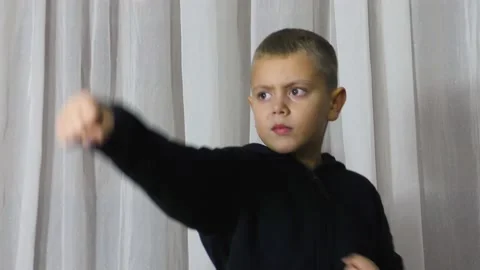 On a light background, an athlete in a black jacket performs punches Video stock 162622313